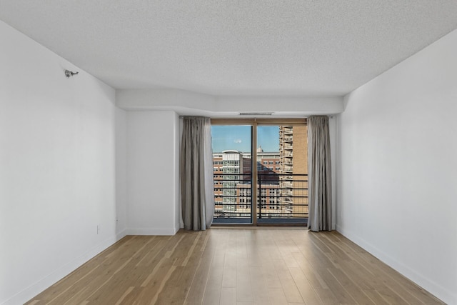 unfurnished room with light wood-type flooring and a textured ceiling