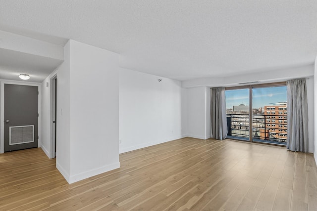 unfurnished room with light hardwood / wood-style flooring and a textured ceiling