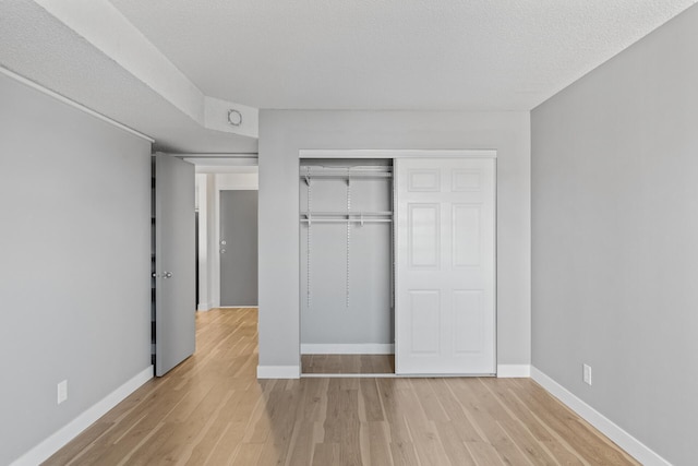 unfurnished bedroom featuring a closet, light hardwood / wood-style floors, and a textured ceiling