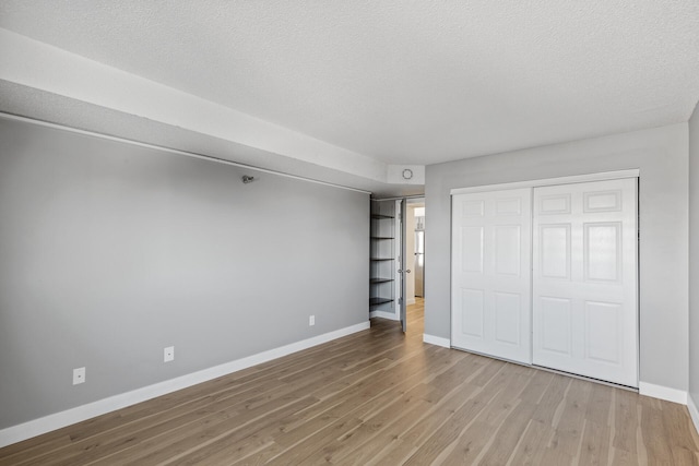 unfurnished bedroom with hardwood / wood-style floors, a closet, and a textured ceiling