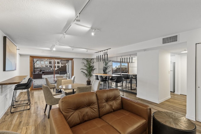 living room featuring track lighting, light hardwood / wood-style flooring, and a textured ceiling