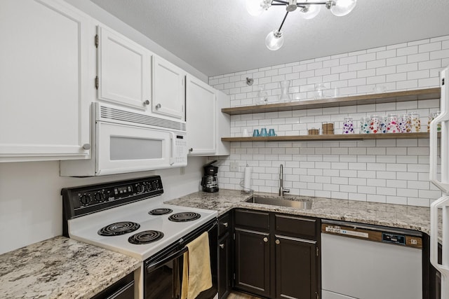 kitchen featuring white appliances, white cabinets, a textured ceiling, sink, and light stone counters