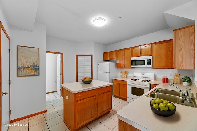 kitchen featuring sink, white appliances, light tile patterned floors, and a kitchen island