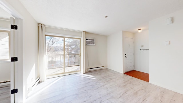 spare room featuring light hardwood / wood-style flooring, a wall unit AC, and baseboard heating