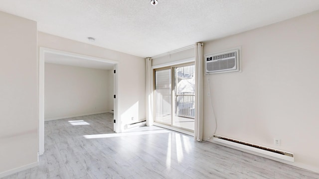 spare room featuring light hardwood / wood-style flooring, an AC wall unit, a textured ceiling, and baseboard heating