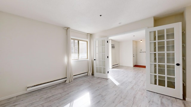 spare room with french doors, a wall mounted AC, baseboard heating, and light wood-type flooring