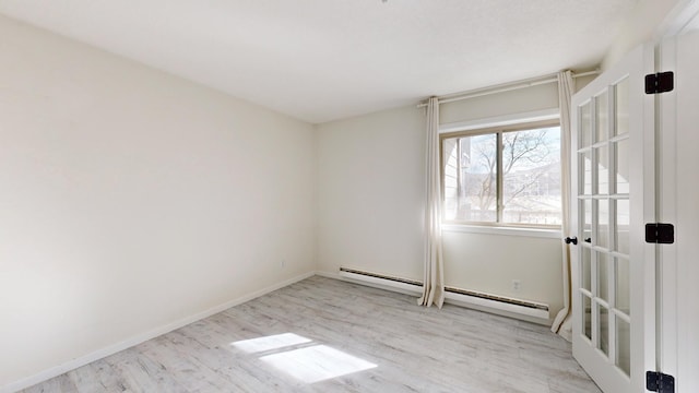 unfurnished room with baseboard heating and light wood-type flooring