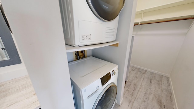 washroom featuring stacked washer and dryer and light hardwood / wood-style floors