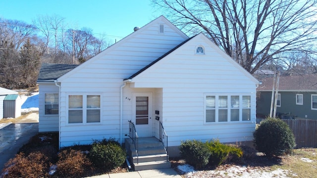 bungalow-style house with a shingled roof and fence