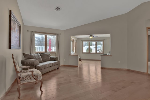 living room with ceiling fan, light hardwood / wood-style flooring, and lofted ceiling