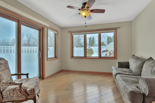 living area with ceiling fan, light hardwood / wood-style flooring, and a textured ceiling