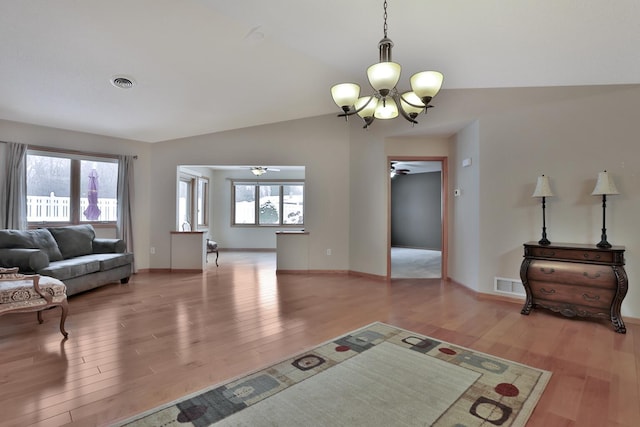 living room with hardwood / wood-style flooring, lofted ceiling, and a notable chandelier