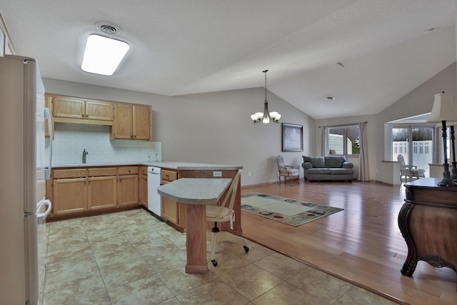 kitchen featuring decorative light fixtures, backsplash, kitchen peninsula, refrigerator, and a notable chandelier