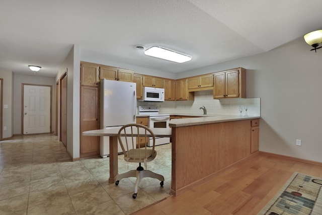 kitchen featuring backsplash, white appliances, sink, and kitchen peninsula