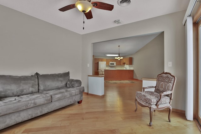 living room with light hardwood / wood-style floors and ceiling fan with notable chandelier