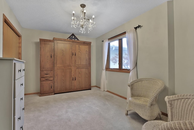 sitting room with light colored carpet, an inviting chandelier, and a textured ceiling