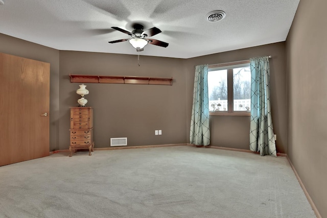 empty room with a textured ceiling, light colored carpet, and ceiling fan