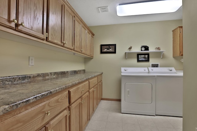 clothes washing area with cabinets and washing machine and clothes dryer