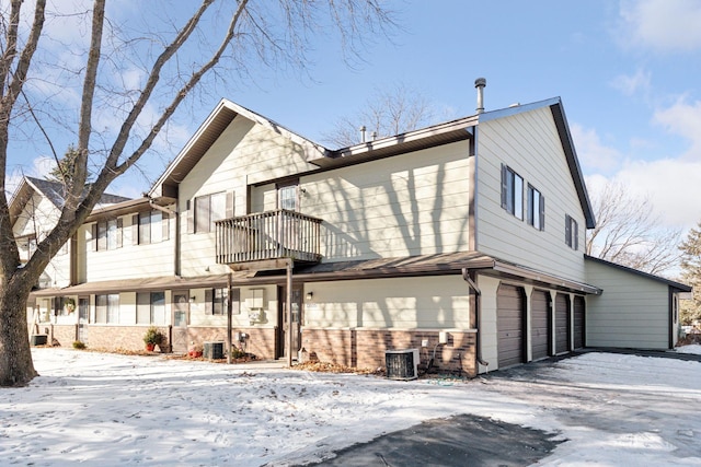 view of front of property with a garage, central AC, and a balcony