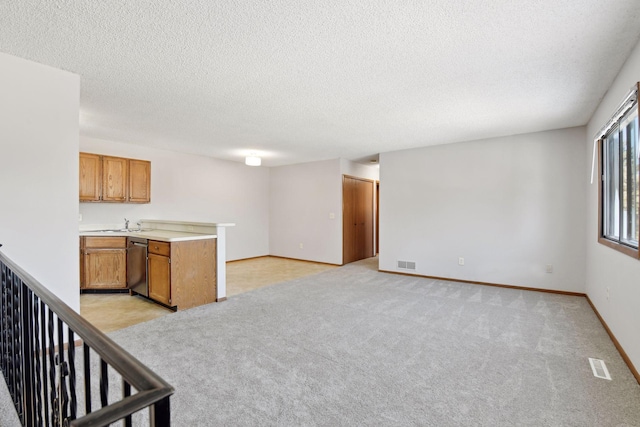 kitchen featuring a textured ceiling, light colored carpet, and dishwasher