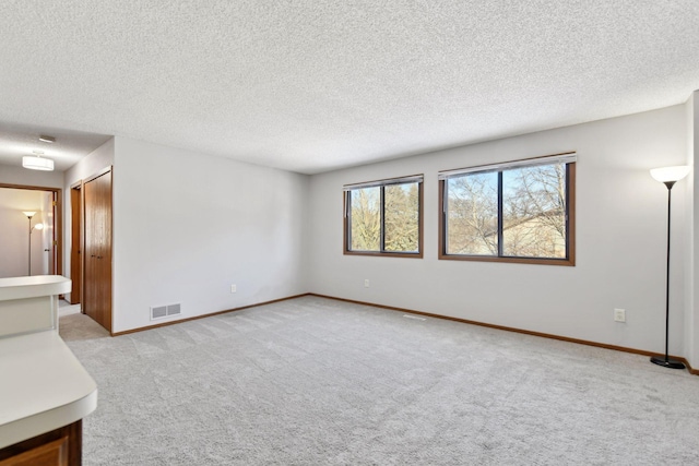 carpeted empty room featuring a textured ceiling