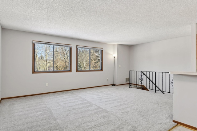 carpeted empty room with a textured ceiling