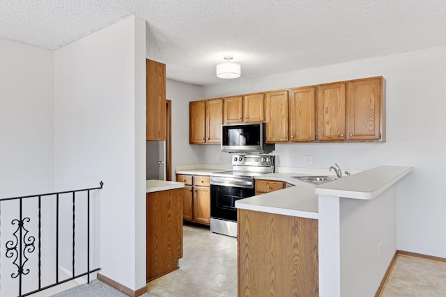 kitchen featuring appliances with stainless steel finishes, sink, a textured ceiling, and kitchen peninsula