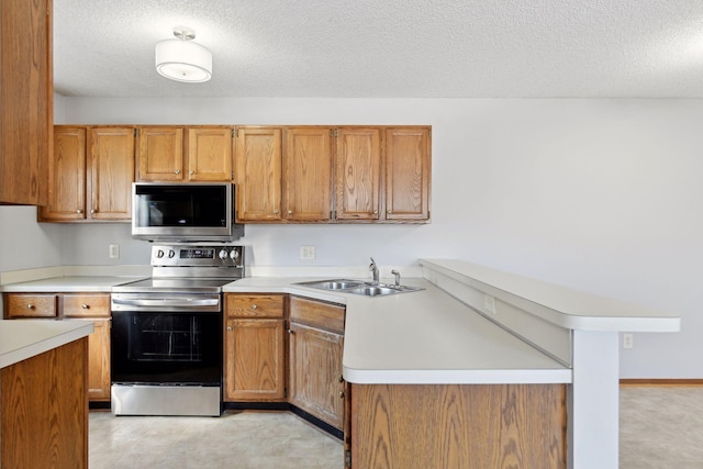 kitchen with appliances with stainless steel finishes, sink, a textured ceiling, and kitchen peninsula