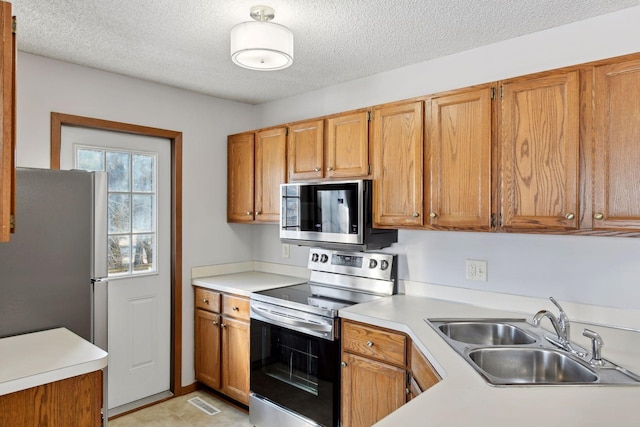 kitchen with appliances with stainless steel finishes, sink, and a textured ceiling