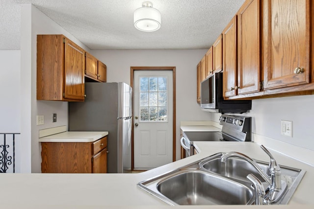 kitchen with sink, a textured ceiling, and appliances with stainless steel finishes