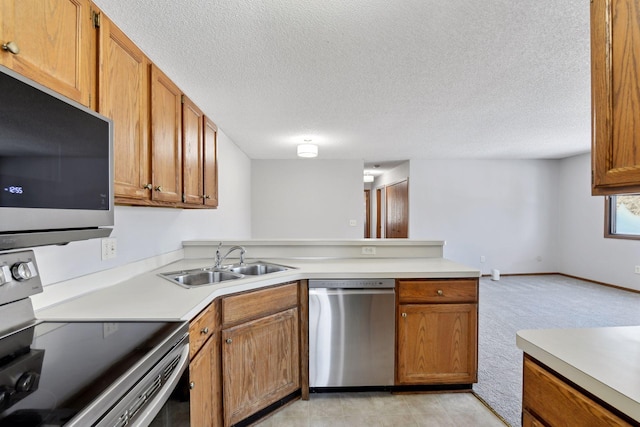 kitchen featuring appliances with stainless steel finishes, sink, light colored carpet, kitchen peninsula, and a textured ceiling