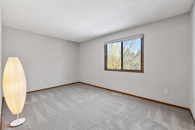 carpeted empty room featuring a textured ceiling