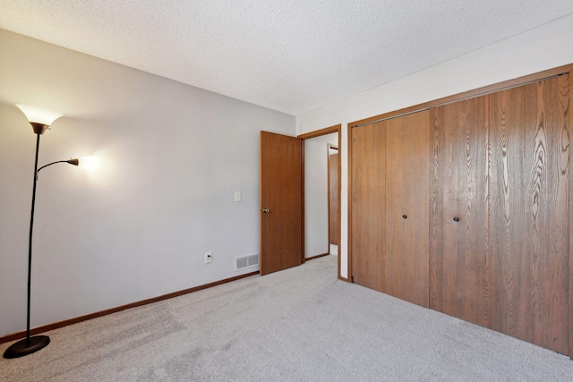 unfurnished bedroom with light colored carpet, a closet, and a textured ceiling