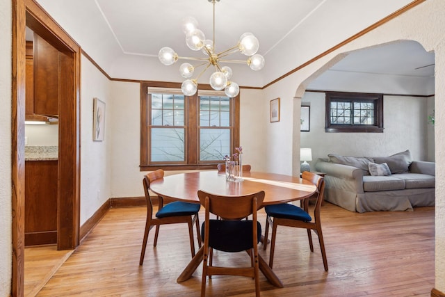 dining room with an inviting chandelier, ornamental molding, and light hardwood / wood-style floors