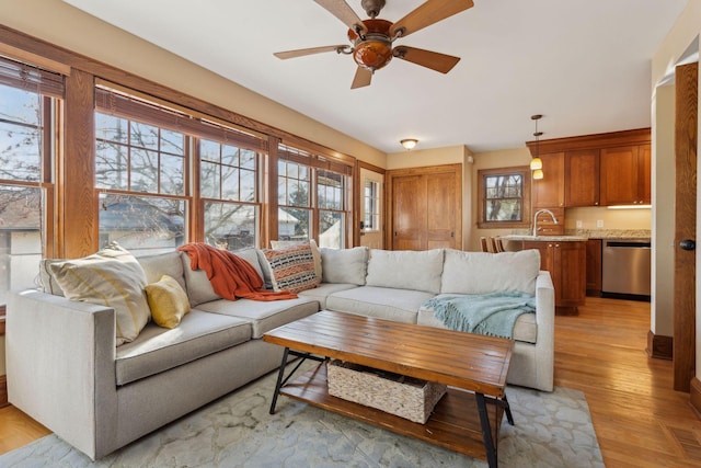 living room with ceiling fan, a healthy amount of sunlight, sink, and light wood-type flooring