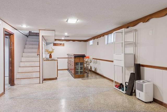 basement featuring bar area and a textured ceiling