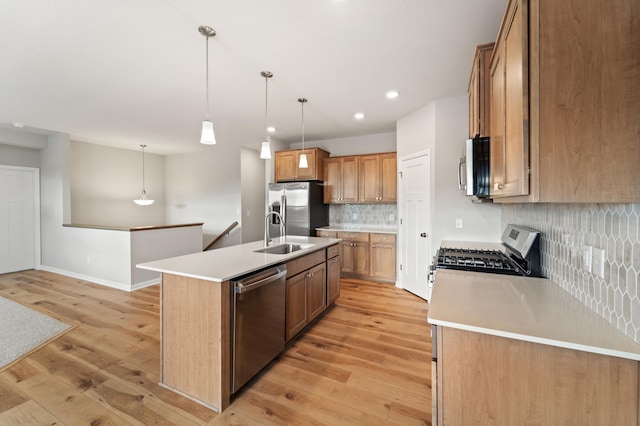 kitchen featuring stainless steel appliances, sink, hanging light fixtures, and a center island with sink