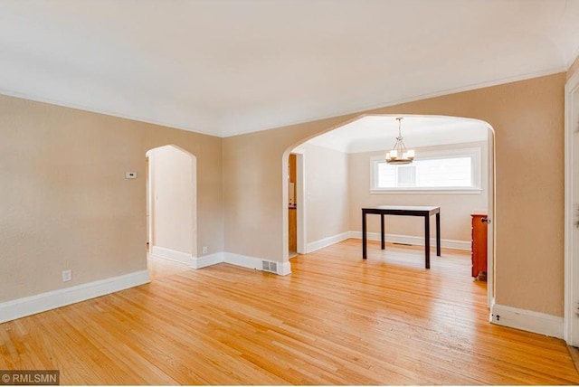 empty room with hardwood / wood-style floors and a chandelier