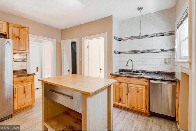 kitchen featuring sink, light hardwood / wood-style flooring, appliances with stainless steel finishes, a kitchen island, and backsplash