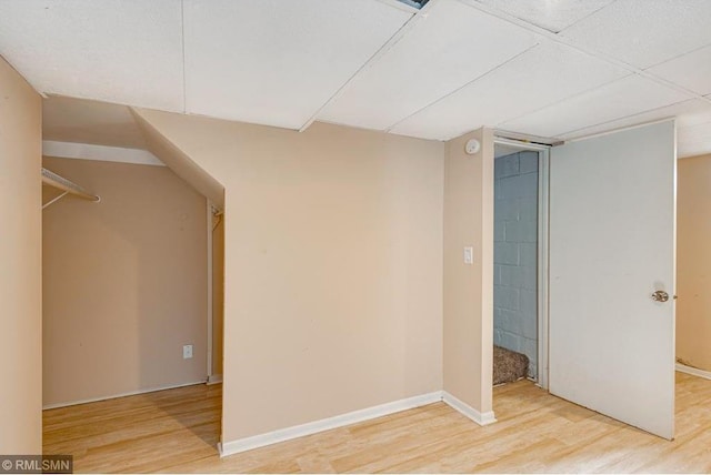 basement featuring a paneled ceiling and hardwood / wood-style floors