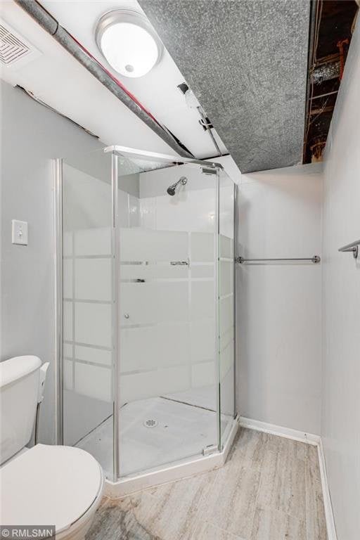 bathroom featuring hardwood / wood-style floors, toilet, and walk in shower