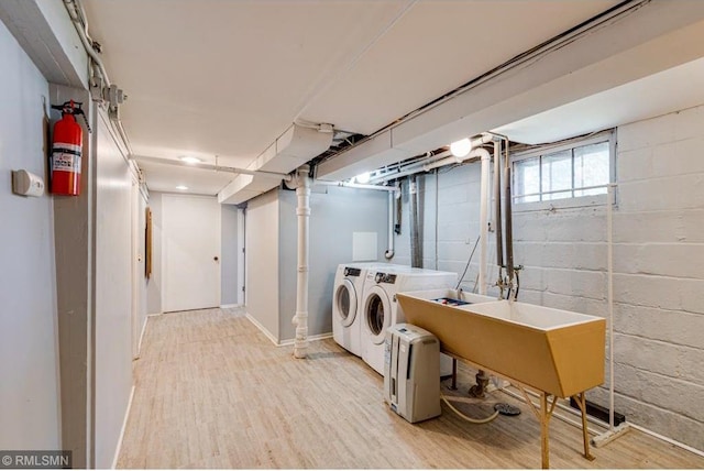 laundry area with sink, washing machine and dryer, and light hardwood / wood-style floors