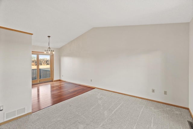 unfurnished room with wood-type flooring, vaulted ceiling, and a notable chandelier