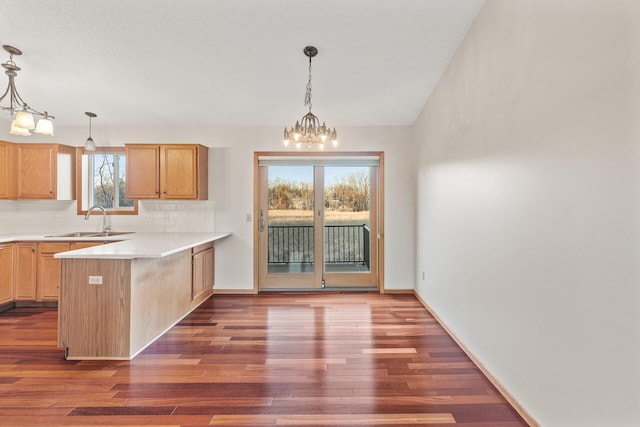 kitchen with sink, hanging light fixtures, kitchen peninsula, and light brown cabinets