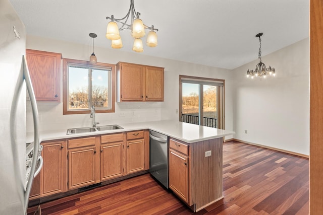 kitchen with appliances with stainless steel finishes, kitchen peninsula, sink, and hanging light fixtures