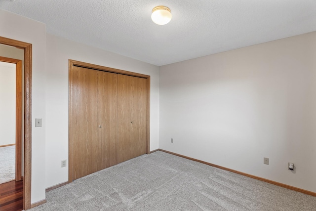 unfurnished bedroom featuring a closet, a textured ceiling, and carpet flooring