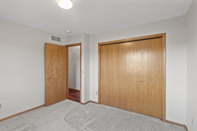 unfurnished bedroom featuring light carpet, a textured ceiling, and a closet