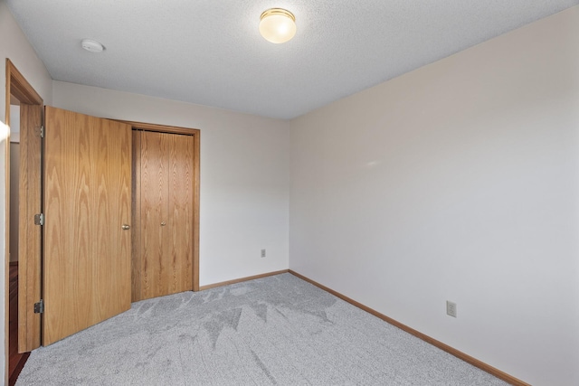 unfurnished bedroom featuring light carpet, a textured ceiling, and a closet