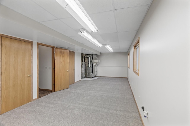 basement with a paneled ceiling, heating unit, and light carpet