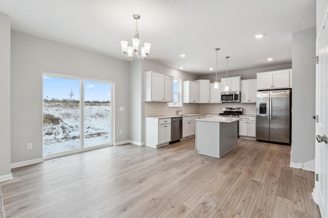 kitchen with appliances with stainless steel finishes, light wood-type flooring, light countertops, and decorative backsplash